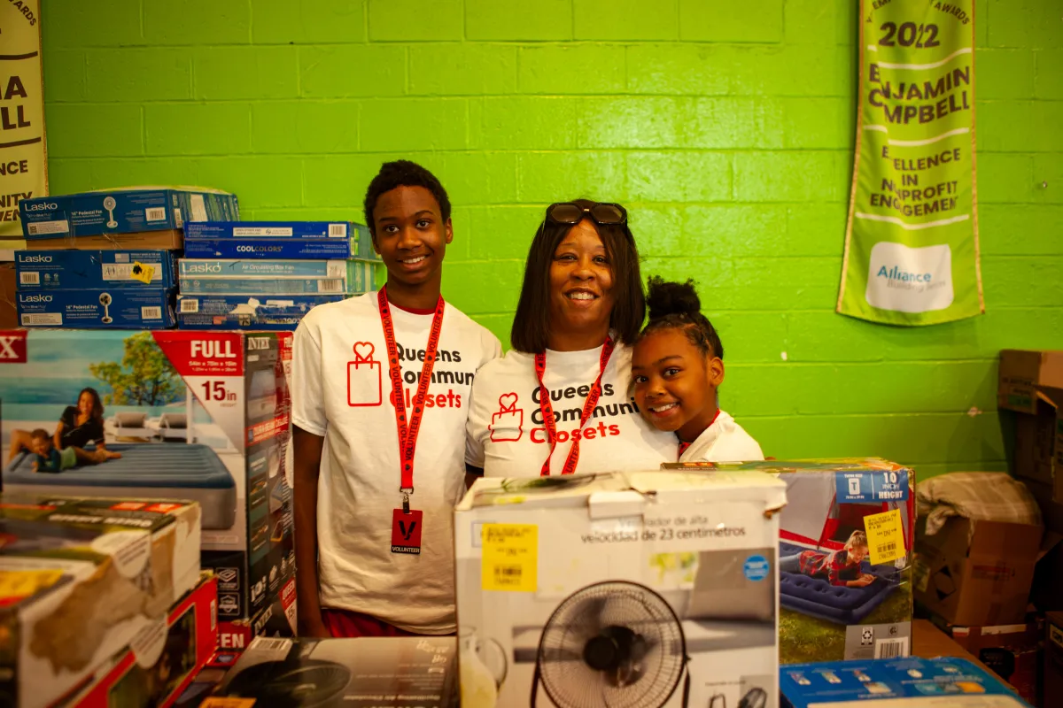 Volunteers in Queens Community Closets shirts standing with donated household supplies